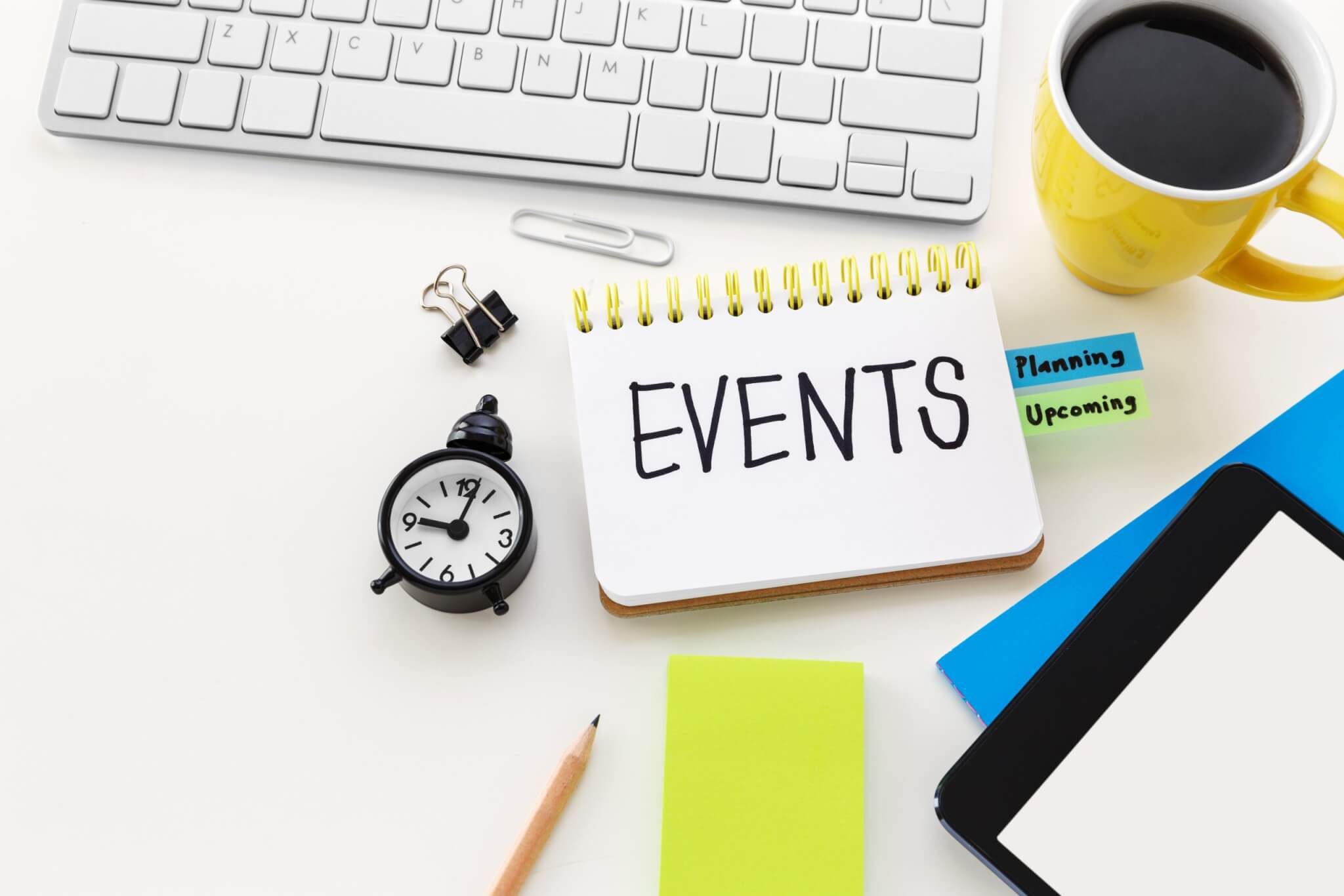 Event planning with clock notepad and coffee cup on computer office desk with space
